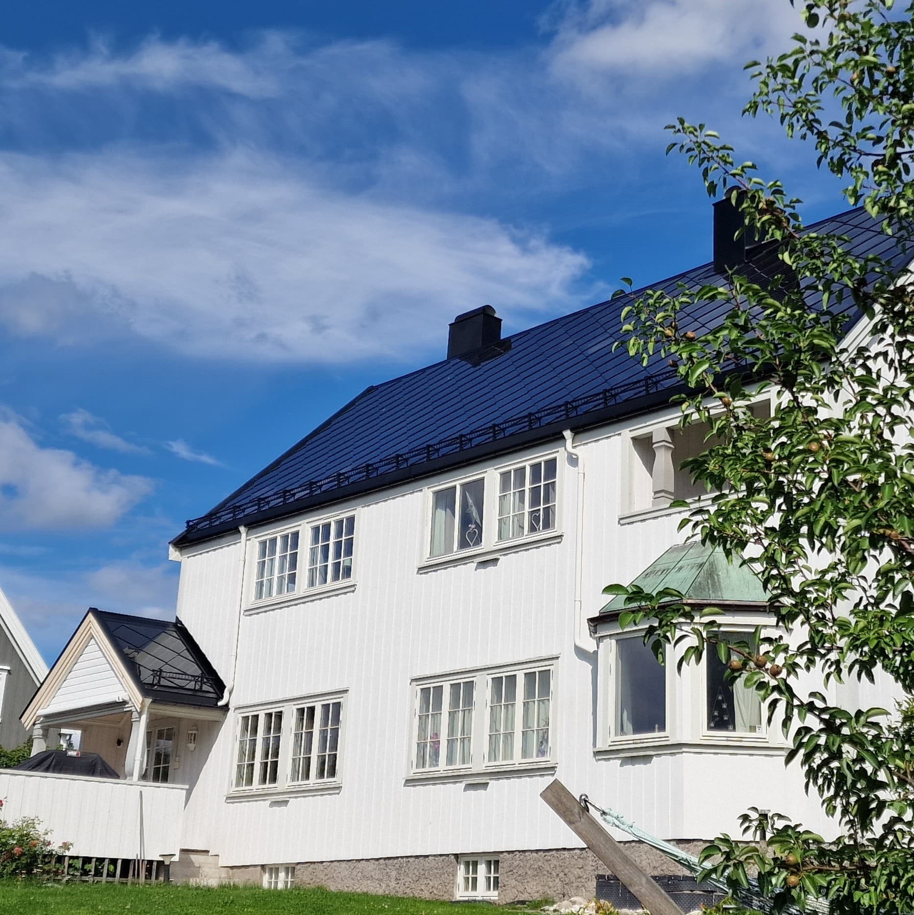 Hvitt verneverdig trehus med rehabilitert Solskifer solcelletak